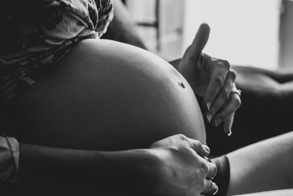 A serene black and white photo capturing a pregnant woman's peaceful moment indoors.