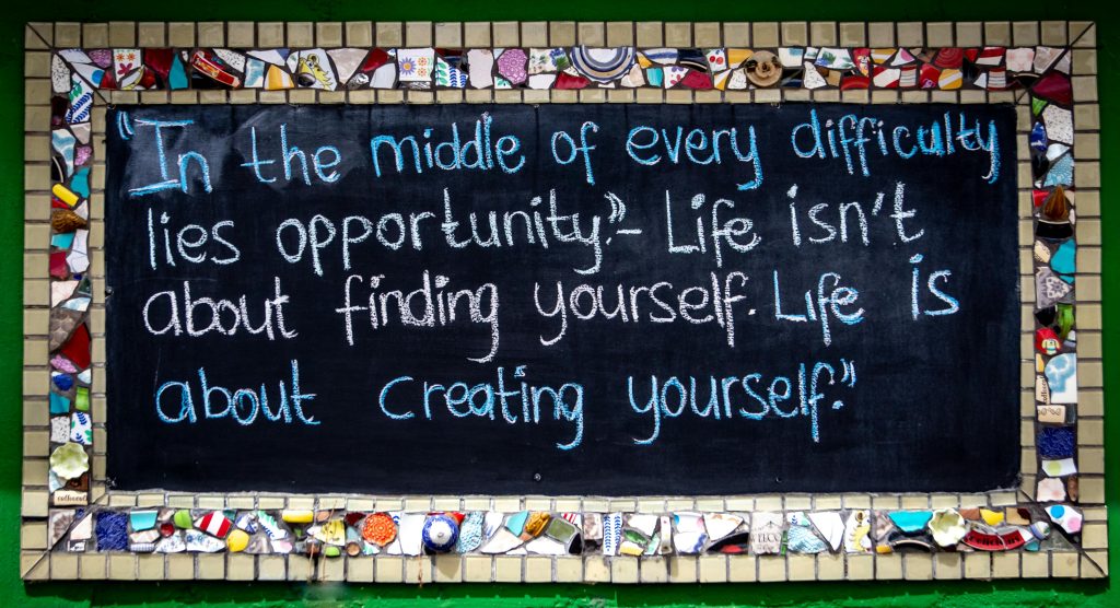 Chalkboard with inspiring quote surrounded by vibrant mosaic pieces.